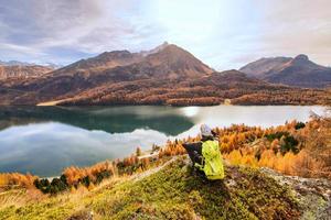 uomo contempla autunno paesaggio nel un' montagna lago foto