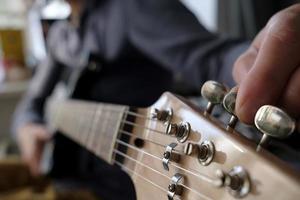 mani sintonizzare il chitarra. riparazione di musicale strumenti. foto