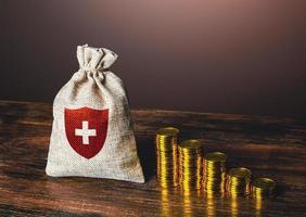 un' pila di monete e un' Borsa di Salute assicurazione. medico vita assicurazione. pagato assistenza sanitaria sistema. raccolta fondi, accumulo di i soldi. sovvenzione e finanziario sostegno. prestiti e crediti per trattamento. foto