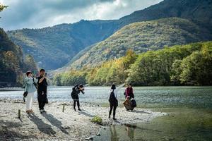 kamikochi, nagano, Giappone - ottobre 2022 non identificato turisti godere con un' bellissimo sfondo di azusa fiume a il centro di kamikochi nazionale parco di neve montagna, rocce, e fiume a partire dal collina. foto