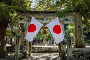Shirakawago, gifu, Giappone - ottobre 2022 - shirakawa hachiman santuario cancello la zona a shirakawago villaggio con pino alberi e giapponese bandiera. foto