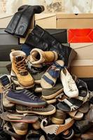 mucchio di vecchio, assortito scarpe su impilati scatole di scarpe. isolato, su il sfondo di un vecchio a brandelli parete. foto
