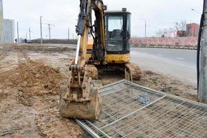 grande luminosa giallo potente industriale pesante scavatrice trattore, bulldozer, specializzato costruzione attrezzatura per strada riparazione durante il costruzione di un' nuovo micro-distretto nel un' grande città foto