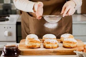 donna prepara fresco ciambelle con marmellata nel casa cucina. cucinando tradizionale ebraico hanukkah sufganiyot. foto