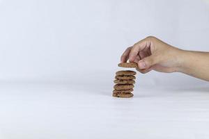 mani impilamento biscotti su un' bianca sfondo. umano mano assunzione avena biscotto a partire dal un' pila foto