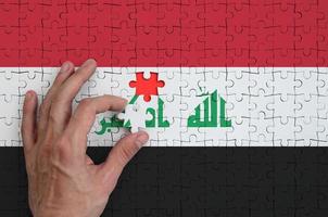 Iraq bandiera è raffigurato su un' puzzle, quale il dell'uomo mano completa per piegare foto