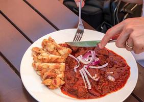 un' uomo mangia Manzo gulasch con ceco Ravioli con un' coltello e forchetta. foto