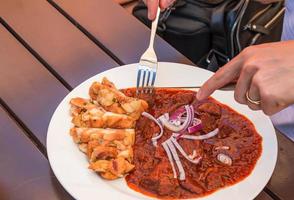 un' uomo mangia Manzo gulasch con ceco Ravioli con un' coltello e forchetta. foto