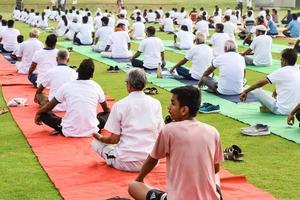 nuovo delhi, India, giugno 21 2022 - gruppo yoga esercizio sessione per persone a yamuna gli sport complesso nel delhi su internazionale yoga giorno, grande gruppo di adulti frequentando yoga classe nel cricket stadio foto