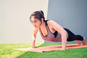 donna pratica push up su un materassino da allenamento all'esterno foto