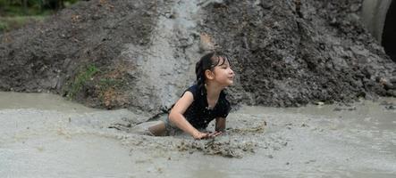 poco ragazze avere divertimento giocando nel il fango nel il Comunità i campi foto