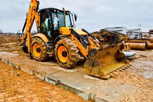 grande luminosa giallo potente industriale pesante scavatrice trattore, bulldozer, specializzato costruzione attrezzatura per strada riparazione durante il costruzione di un' nuovo micro-distretto nel un' grande città foto