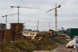 un' grande moderno costruzione luogo nel il costruzione di edifici e case con elettrodomestici e molti grande alto Torre e stazionario industriale potente gru e edificio materiale foto