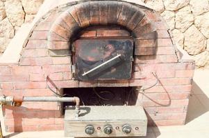 un' grande professionale industriale Marrone pietra forno griglia forno con un' tubo per cucinando frittura cibo a partire dal un' pietra piastrelle su un' pietra parete sfondo nel il Aperto aria strada foto