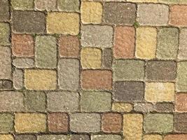 struttura di multicolore bellissimo rettangolare pietra calcestruzzo pavimentazione mattone piastrelle con cuciture coperto di vegetazione con verde erba. il sfondo foto
