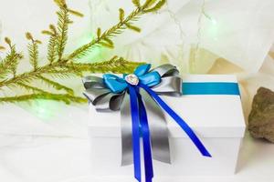 un' Natale regalo decorato con un' bellissimo arco su un' leggero sfondo con un' ramoscello, Se. selettivo messa a fuoco. il concetto di Natale e nuovo anno. foto