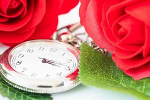 primo piano orologio da tasca e fiori di rose rosse foto