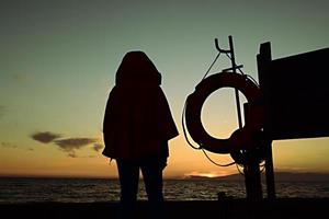 persona silhouette in piedi vicino al mare foto