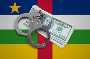 centrale africano repubblica bandiera con manette e un' fascio di dollari. moneta corruzione nel il nazione. finanziario crimini foto