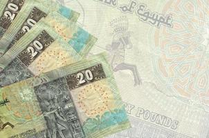 20 egiziano sterline fatture bugie nel pila su sfondo di grande semi trasparente banconota. astratto attività commerciale sfondo foto