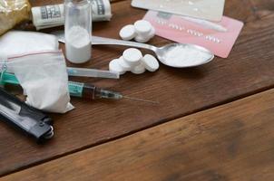 un' lotto di narcotico sostanze pillole e dispositivi per il preparazione di farmaci menzogna su un vecchio di legno tavolo foto