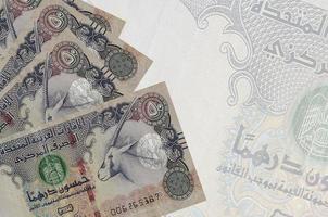 50 Emirati Arabi Uniti dirham fatture bugie nel pila su sfondo di grande semi trasparente banconota. astratto attività commerciale sfondo foto