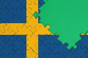 Svezia bandiera è raffigurato su un' completato sega puzzle con gratuito verde copia spazio su il giusto lato foto