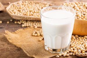 soia latte nel un' bicchiere con semi di soia su un' di legno tavolo biologico colazione, alto proteina, sano, agricolo prodotti, vegetariano foto