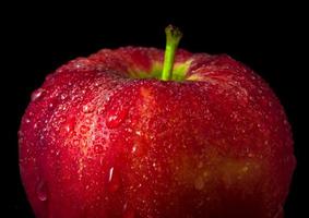 goccia d'acqua sulla superficie lucida della mela rossa su sfondo nero foto
