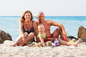 poco ragazza con nonni su il spiaggia foto