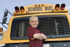 studente elementare in piedi da scuolabus foto