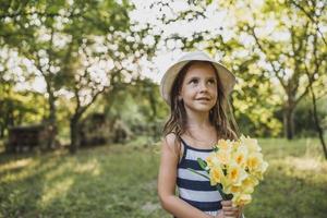 poco ragazza con mazzo di giunchiglie nel natura foto