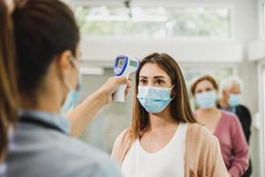 giovane donna avendo sua temperatura verificato prima covid-19 vaccino foto