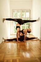 femmina Gemelli l'esecuzione Diviso esercizi mentre fare yoga foto