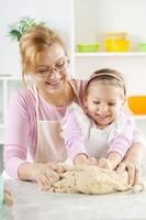 contento poco ragazza con nonna nel il cucina foto