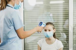 adolescente ragazza avendo sua temperatura verificato prima covic-19 vaccino foto