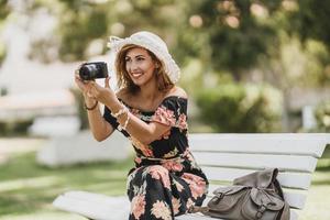 donna assunzione fotografie con digitale telecamera mentre seduta su un' panchina nel il parco