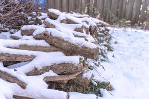 asciutto legna da ardere e neve nel il inverno, impilati nel il Giardino dietro la casa. foto