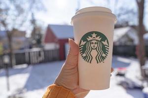 marinette,wi,usa - nov14, 2019- tazze di Starbucks caldo caffè mettere su bianca neve nel inverno giardino, fresco e caldo bevanda prendere lontano concept.starbucks bar caffè negozio. foto