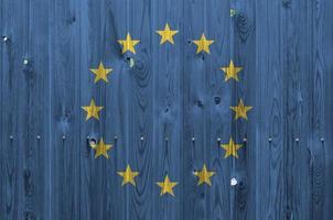 europeo unione bandiera raffigurato nel luminosa dipingere colori su vecchio di legno parete. strutturato bandiera su ruvido sfondo foto