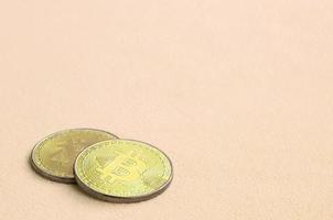 Due d'oro bitcoin bugie su un' coperta fatto di morbido e soffice leggero arancia vello tessuto. fisico visualizzazione di virtuale crypto moneta foto