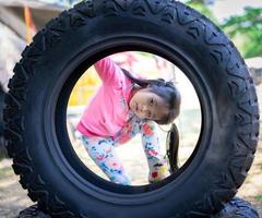 piccola ragazza asiatica guardando attraverso un pneumatico foto