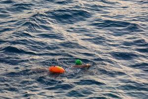 nuotatore nuoto nel Aperto acqua nel il mediterraneo mare con un' sicurezza boa foto