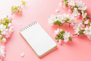 fioritura primavera sakura su un' rosa sfondo con bloc notes spazio per saluto Messaggio. il concetto di primavera e La madre di giorno. bellissimo delicato rosa ciliegia fiori nel primavera foto