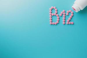 rosa pillole nel il forma di il lettera b12 su un' blu sfondo, rovesciato su di un' bianca Potere, Basso contrasto foto