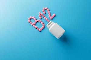 rosa pillole nel il forma di il lettera b12 su un' blu sfondo, rovesciato su di un' bianca Potere. foto