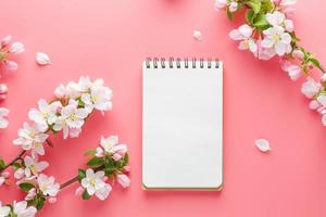 fioritura primavera sakura su un' rosa sfondo con bloc notes spazio per saluto Messaggio. il concetto di primavera e La madre di giorno. bellissimo delicato rosa ciliegia fiori nel primavera foto