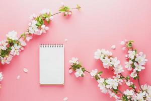 fioritura primavera sakura su un' rosa sfondo con bloc notes spazio per saluto Messaggio. il concetto di primavera e La madre di giorno. bellissimo delicato rosa ciliegia fiori nel primavera foto