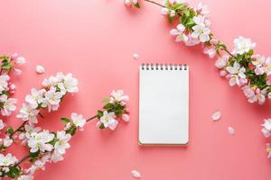 fioritura primavera sakura su un' rosa sfondo con bloc notes spazio per saluto Messaggio. il concetto di primavera e La madre di giorno. bellissimo delicato rosa ciliegia fiori nel primavera foto