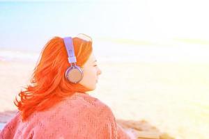 bella donna che ascolta la musica sulla spiaggia. foto